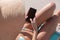 Mid section of caucasian woman using smartphone while sitting on deck chair at the beach