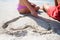 Mid section of couple sitting by heart shape carved on sand at beach