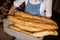 Mid-section of female staff holding basket of baguettes in bakery section