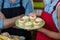 Mid section of female staff holding a plate of cupcakes