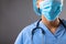 Mid section of female surgeon wearing face mask against grey background