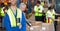 Mid section of happy caucasian worker wearing yellow vest in an warehouse in front of hid colleagues