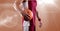 Mid section of male basketball player holding basketball against spot of light in background