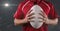 Mid section of male rugby player holding ball against smoke and light spot on grey background