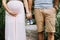 mid section photo of pregnant wife and her husband carrying tiny baby shoes