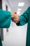 Mid section of surgeons shaking hands in corridor