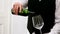 Mid section of waiter pouring red wine into a wine glass at counter