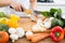 Mid section of a woman chopping vegetables in kitchen