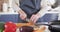 Mid section of woman wearing apron chopping vegetables in the kitchen at home