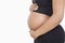 Mid section of young pregnant woman with hands on stomach over white background