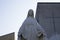 Mid shot of a white statue of Mary with a  building with a cross in the background