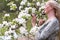 middel aged woman stands in the park next to a flowering tree, Spring time