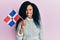 Middle age african american woman holding dominican republic flag looking positive and happy standing and smiling with a confident