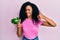 Middle age african american woman holding green pepper smiling happy and positive, thumb up doing excellent and approval sign