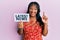 Middle age african american woman holding latest news message on paper smiling with an idea or question pointing finger with happy