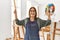 Middle age artist woman smiling happy painting at art studio