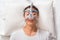 middle age asian man sleeping in his bed wearing CPAP mask connecting to air hose, device for people with sleep apnea