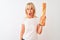 Middle age baker woman holding bread standing over isolated white background scared in shock with a surprise face, afraid and