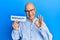 Middle age bald man holding paper with spirituality word doing ok sign with fingers, smiling friendly gesturing excellent symbol