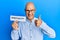 Middle age bald man holding paper with spirituality word smiling happy and positive, thumb up doing excellent and approval sign