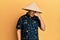Middle age bald man wearing traditional asian straw hat surprised with hand on head for mistake, remember error