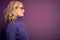 Middle age beautiful blonde woman wearing casual purple turtleneck sweater and glasses looking to side, relax profile pose with