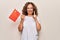 Middle age beautiful patriotic woman holding chinese flag over isolated white background smiling with an idea or question pointing