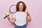 Middle age beautiful sportswoman playing tennis holding racket and ball over white background smiling happy and positive, thumb up