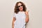 Middle age beautiful woman wearing funny thug life sunglasses over white background pointing thumb up to the side smiling happy