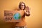 Middle age blonde woman asking for the enviroment holding banner with earth day message with open hand doing stop sign with