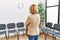 Middle age blonde woman on back view looking clock at waiting room