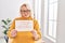 Middle age blonde woman business worker smiling confident holding stop harassement banner at office