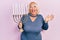 Middle age blonde woman holding menorah hanukkah jewish candle celebrating achievement with happy smile and winner expression with