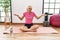 Middle age blonde woman sitting on yoga mat smiling cheerful offering hands giving assistance and acceptance