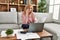 Middle age blonde woman teleworking using laptop and talking on the smartphone at home