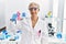 Middle age blonde woman working at laboratory looking for breast cancer cure looking positive and happy standing and smiling with