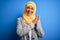 Middle age brunette business woman wearing muslim traditional hijab over blue background clapping and applauding happy and joyful,