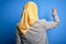 Middle age brunette business woman wearing muslim traditional hijab over blue background Posing backwards pointing ahead with