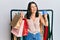 Middle age brunette personal shopper woman holding shopping bags and credit card smiling and laughing hard out loud because funny