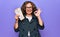 Middle age brunette tourist woman holding airline boarding pass for holidays over purple background doing ok sign with fingers,