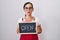 Middle age brunette woman holding banner with open text thinking attitude and sober expression looking self confident