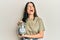 Middle age brunette woman holding charity jar with money angry and mad screaming frustrated and furious, shouting with anger