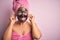 Middle age brunette woman wearing beauty black face mask over isolated pink background Smiling pulling ears with fingers, funny