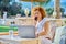 Middle age business woman using outdoor laptop talking on smartphone