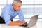 Middle Age Businessman leaning on desk with Laptop