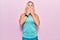 Middle age caucasian blonde woman wearing sports clothes over pink background shocked covering mouth with hands for mistake