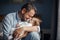 Middle age Caucasian father kissing sleeping newborn baby girl. Parent holding rocking child daughter son in hands. Authentic