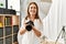 Middle age caucasian woman photographer smiling confident holding professional camera at photograph studio