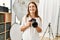 Middle age caucasian woman photographer smiling confident holding professional camera at photograph studio