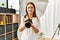 Middle age caucasian woman photographer smiling confident holding professional camera at photograph studio